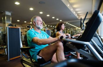 man at gym exercising on a recumbent stepper exercise machine