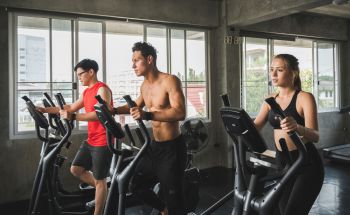 Group of people at the gym exercising on elliptical machines